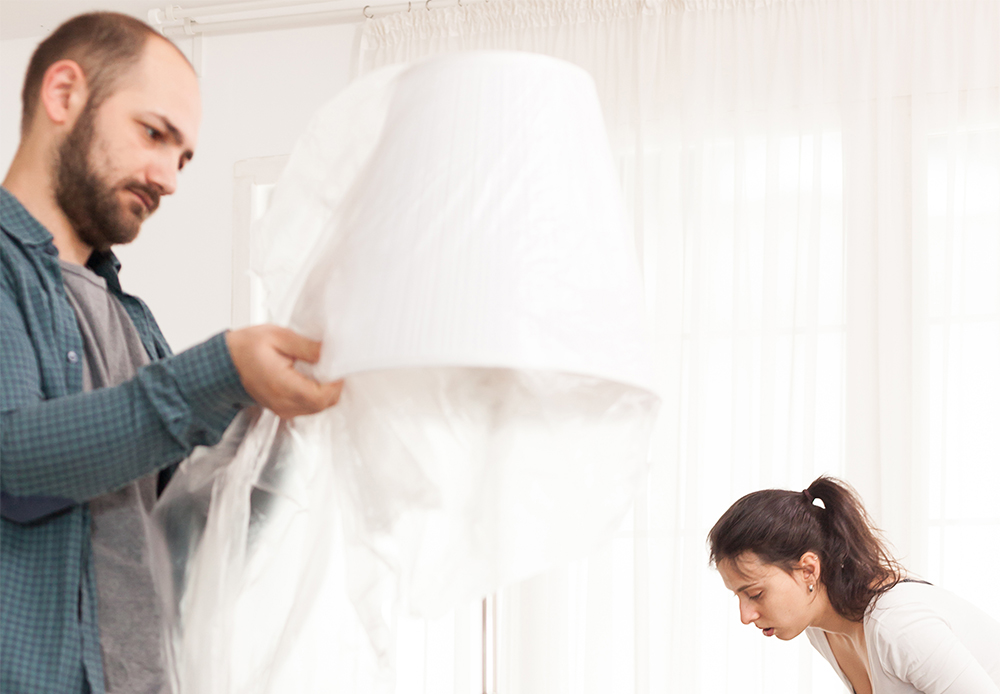 Man Wrapping Lamp In Plastic Sheet